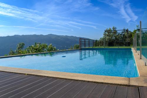 een groot blauw zwembad met bergen op de achtergrond bij Quinta das Regadinhas in Cinfães