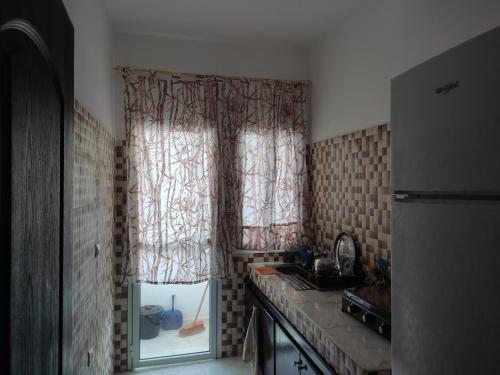 a kitchen with a sink and a window with curtains at Peaceful Apartment in Al Hoceïma