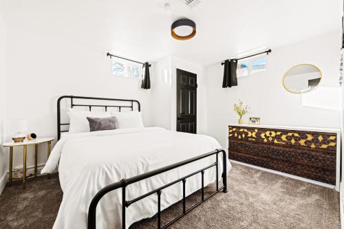 a white bedroom with a black bed and a mirror at New Colorful Home - Backyard Oasis - City Park in Denver