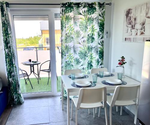a dining room with a white table and chairs and a window at Apartament HARPUN nad morzem in Rusinowo