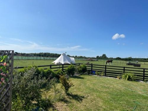 uma tenda branca num campo ao lado de uma cerca em Betrice Bell Tent em Poulton le Fylde