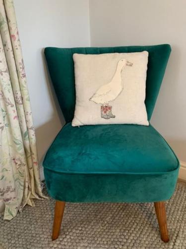 a green chair with a pillow with a bird on it at Cliff Stud Retreat - Luxury lodges and cosy cottages in Helmsley