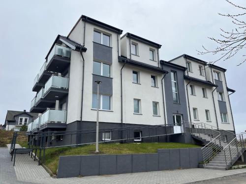 a large white building with stairs in front of it at Apartament HARPUN nad morzem in Rusinowo
