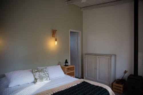 1 dormitorio con cama blanca y mesita de noche en Estancia La Titina, Posada y Reserva Natural en Concepción del Uruguay