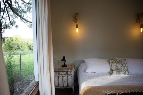 um quarto com uma cama ao lado de uma janela em Estancia La Titina, Posada y Reserva Natural em Concepción del Uruguay