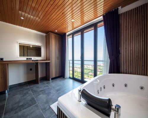 een grote badkamer met een bad en een groot raam bij Royal Villa in Trabzon