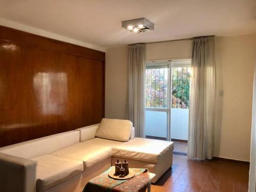 Una sala de estar con un sofá blanco y una ventana. en Amplio Departamento Céntrico, en San Juan