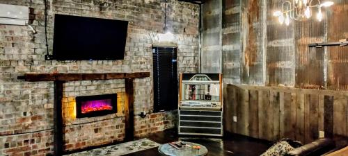Hocking Hills Rusty Lofts في لوغان: غرفة معيشة مع جدار من الطوب مع موقد