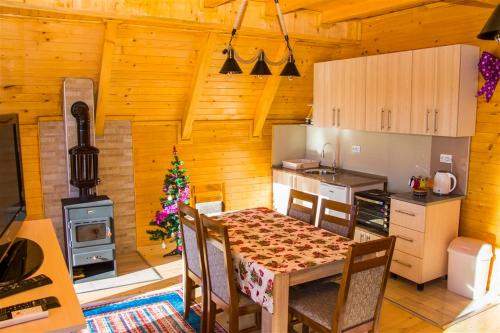 een eetkamer met een tafel en een keuken bij ROMANIJA - Brvnara za odmor in Han Pijesak