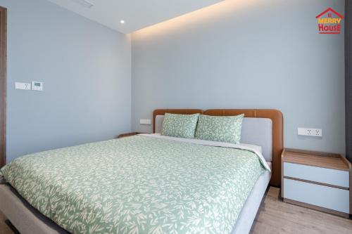 a bedroom with a bed with a green comforter and pillows at Merry House Harmony in Ðông Khê