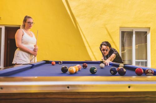 a man and a woman standing next to a pool table at The Macarena Beach Hostel in Lagos