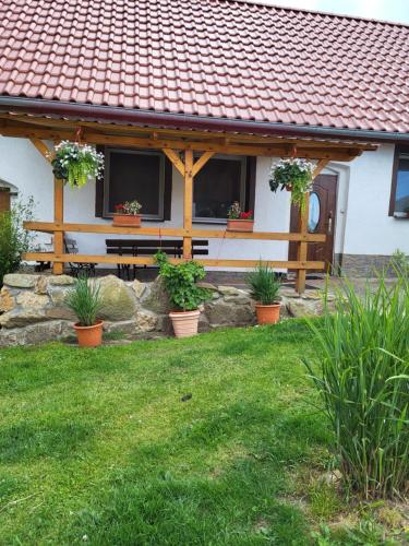 a house with a bench and plants in a yard at Agroturystyka Nad strumykiem in Leśna