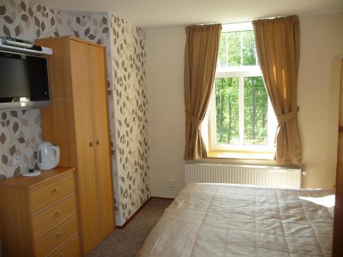 a bedroom with a bed with a dresser and a window at BLUE PENSiON in Svoboda nad Úpou