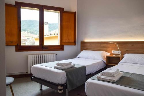 a hotel room with two beds and a window at Can Severí casa con historia en Besalú in Besalú