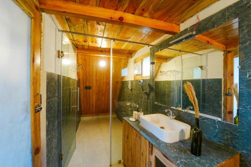 a bathroom with a sink and a glass shower at Himalayan Manor A-Frame House in Sainj