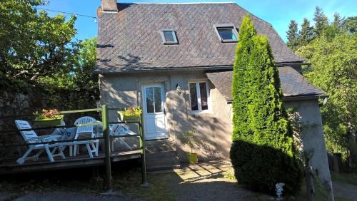 a small house with a porch and two chairs at Maison de campagne in Sénergues