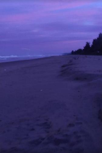 an empty beach at night with a purple sky at Ocean Sparrow Beach Stay in Gokarna