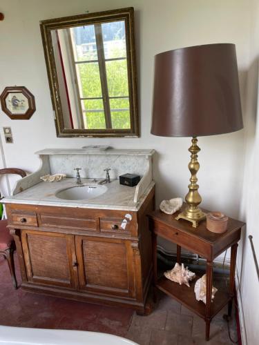La salle de bains est pourvue d'un lavabo et d'une lampe sur une table. dans l'établissement La Maison du meunier, à Romorantin-Lanthenay