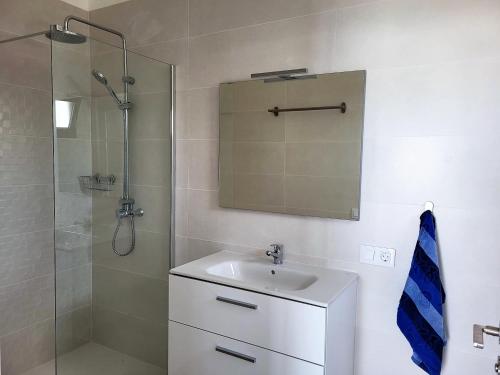 een badkamer met een wastafel en een douche met een spiegel bij Apartamentos Falcón in Tinajo
