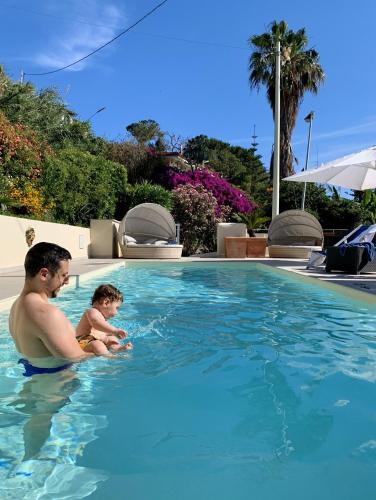 a man and a baby in a swimming pool at HOTEL MERCURIO SUL MARE - Fish restaurant and private beach in Capo Vaticano