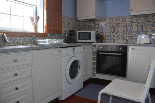 a kitchen with a washing machine and a microwave at Alojamento Local de Santa Catarina in Praia da Vitória
