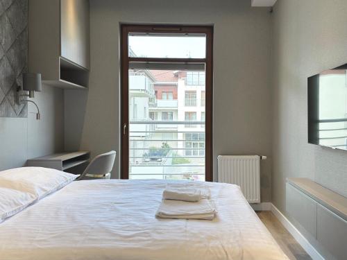 a bedroom with a white bed with a window at Neptun Park- Apartament Elegance in Gdańsk