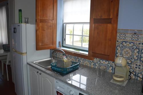 a kitchen with a sink and a white refrigerator at Alojamento Local de Santa Catarina in Praia da Vitória
