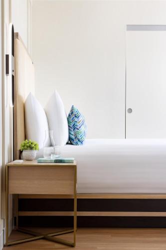 a bed with white pillows and a table in a room at The Anza-a Calabasas Hotel in Calabasas