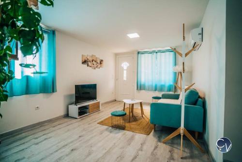 un salon avec un canapé bleu et une télévision dans l'établissement Maison rénovée à 500 m du centre du village, à Goudargues