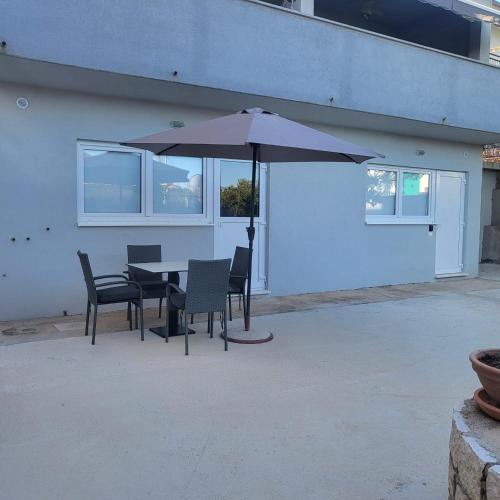 een patio met een tafel en stoelen en een parasol bij Bepina in Gradac