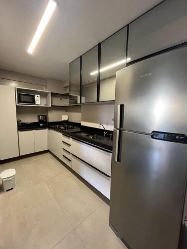 a kitchen with a stainless steel refrigerator and white cabinets at Lindo terraço perto do mar in João Pessoa