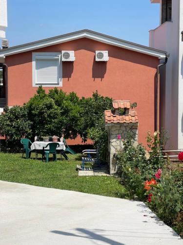 a red house with a table and chairs in the yard at Lulu Garden in Ulcinj