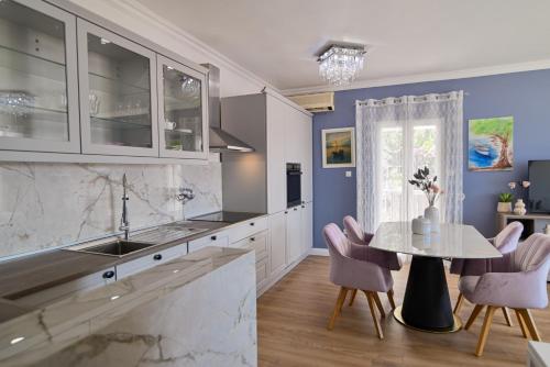 uma cozinha com um lavatório e uma mesa com cadeiras em Apartment Spira Puovica em Trogir