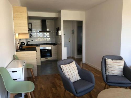 a living room with two chairs and a kitchen at A Estrenar. Apartamento Reformado con vistas. in Salinas