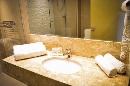 a bathroom with a sink and a mirror and towels at Sky Valle Hotel in Gramado