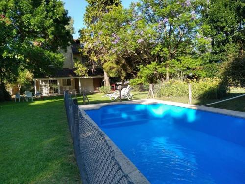 a blue swimming pool with a fence next to a yard at Casa amplia - Pileta y parque in Bella Vista