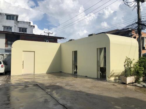 a white building with two doors in a parking lot at Polkadot Hostel in Phitsanulok