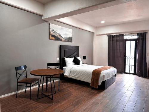 a bedroom with a bed and a table and chairs at Hotel Santa María in Taxco de Alarcón
