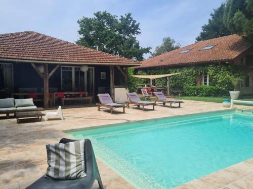 einen Pool mit Stühlen und ein Haus in der Unterkunft Maison Pimoli : Chambre Garance in Soustons