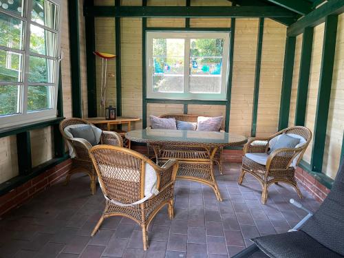 a screened in porch with wicker chairs and a table at Ferienwohnung Zur Heide in Rheine