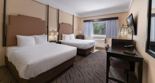 a hotel room with two beds and a desk at Prestige Inn Golden in Golden