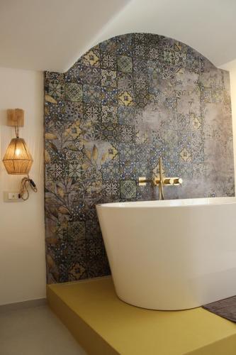 a bath tub in a bathroom with a mosaic wall at Il Palazzotto in Fasano