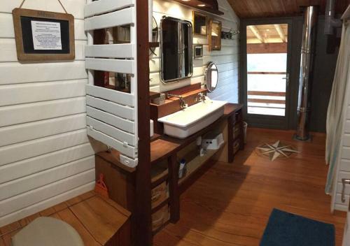 une salle de bain avec un lavabo et une télévision au mur dans l'établissement La Maison de l'Aérogrange, à Biscarrosse