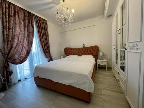 - une chambre avec un grand lit et un lustre dans l'établissement Lux apartament, à Focşani