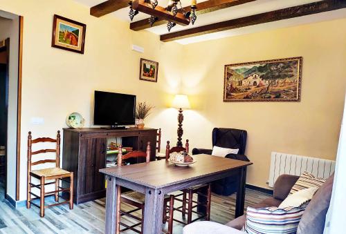 Casa Rural Los Mayorales في Esparragalejo: غرفة معيشة مع طاولة وتلفزيون