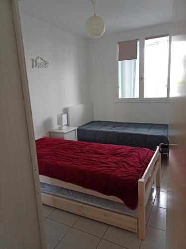 une chambre avec un lit avec une couverture rouge dans l'établissement APPARTEMENT BORD DE MER, à Saint-Hilaire-de-Riez