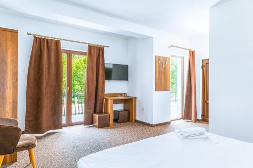um quarto com uma cama, uma televisão e janelas em Vila Venus em Sânmartin