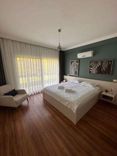 a bedroom with a large white bed and a chair at HESTİA ILICA in Cesme