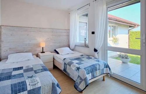 Duas camas num quarto com uma grande janela. em Villa Victoria em Rowy