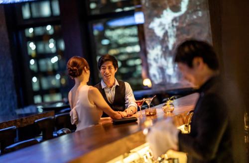 a bride and groom standing at a bar in a restaurant at InterContinental Hotel Osaka by IHG in Osaka